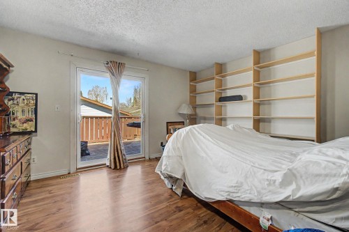 Room featuring wood-finish flooring, built-in shelving, and a sliding glass door providing access to an outdoor patio with a privacy fence - 4106 38 Street, Edmonton, AB - Indoor Photo Showing Bedroom