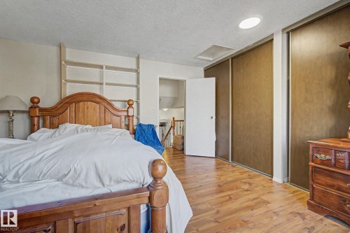 Bedroom featuring wood-finish flooring, built-in shelving, a recessed ceiling light, and sliding closet doors - 4106 38 Street, Edmonton, AB - Indoor Photo Showing Bedroom