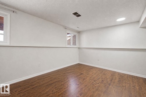 Room featuring wood-finish flooring, two windows with white trim, white baseboards, and a recessed ceiling light - 4106 38 Street, Edmonton, AB - Indoor Photo Showing Other Room
