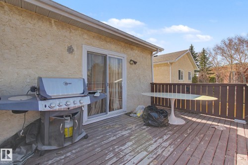Outdoor deck featuring wood planking, a brown privacy fence, and direct access to the interior via a sliding glass door - 4106 38 Street, Edmonton, AB - Outdoor With Deck Patio Veranda With Exterior