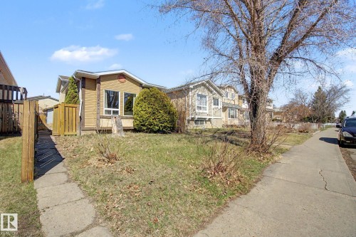 Exterior property featuring tan siding, a concrete pathway, a wooden fence, and established landscaping - 4106 38 Street, Edmonton, AB - Outdoor
