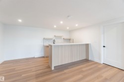 Contemporary wet bar featuring light wood-finish cabinetry, a white countertop, and a matte black faucet - 