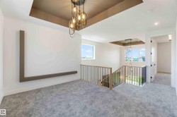 Spacious upper-level landing with plush gray carpeting and a contemporary chandelier - 