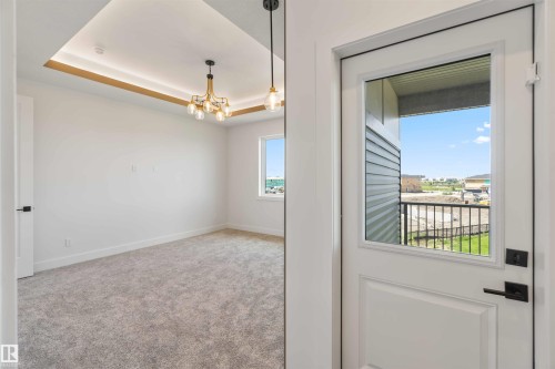 Room featuring a tray ceiling with recessed lighting and a contemporary chandelier - 74 Eldridge Point(E), St. Albert, AB - Indoor Photo Showing Other Room