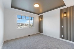 Spacious room featuring a white window frame, contemporary ceiling design, modern flush-mount light fixture, and two decorative wall sconces illuminating fluted wall panels - 