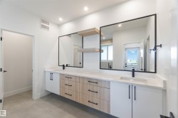 Spacious bathroom featuring a dual vanity with quartz countertops, undermount sinks, and matte black fixtures - 