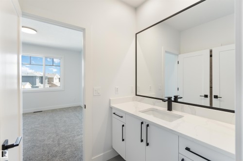 Contemporary vanity featuring a rectangular undermount sink, quartz countertop, matte black faucet, and a large framed mirror - 74 Eldridge Point(E), St. Albert, AB - Indoor Photo Showing Bathroom