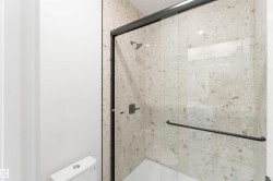 Glass-enclosed shower with black-framed sliding door and matching handle - 