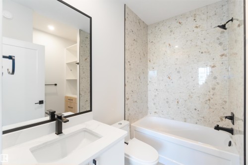 Bathroom featuring a white vanity with an integrated sink, black faucet, and a large framed mirror - 74 Eldridge Point(E), St. Albert, AB - Indoor Photo Showing Bathroom
