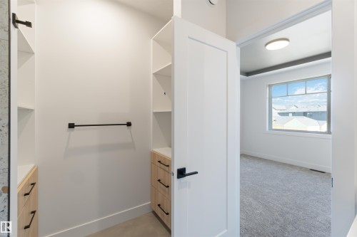 Walk-in closet with built-in shelving, light wood-finish drawers, and matte black hardware - 74 Eldridge Point(E), St. Albert, AB - Indoor