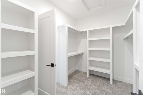 Custom closet system with built-in shelving, hanging rods, and a neutral carpeted floor - 74 Eldridge Point(E), St. Albert, AB - Indoor With Storage