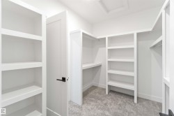 Custom closet system with built-in shelving, hanging rods, and a neutral carpeted floor - 