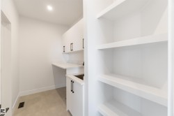Utility room featuring white cabinetry with black hardware, a built-in sink, and a countertop workspace - 