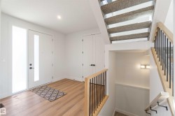 Entryway featuring wood-finish flooring, a contemporary front door with frosted glass panel, and a coordinated sidelight - 