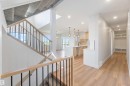 Open-concept interior featuring wood-finish flooring, a modern staircase with wood handrails and black balusters, recessed lighting, a contemporary kitchen with light-toned cabinetry and pendant lights, and a built-in storage bench - 74 Eldridge Point(E), St. Albert, AB  - Indoor Photo Showing Other Room 
