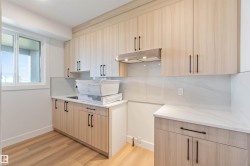 Utility room featuring wood-finish cabinetry with black hardware, white countertops, and a white tile backsplash - 