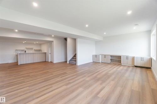 Spacious open-concept lower level featuring wood-finish flooring, recessed lighting, and a built-in wet bar with upper shelving - 74 Eldridge Point(E), St. Albert, AB - Indoor Photo Showing Other Room