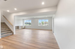 Spacious room featuring light wood-finish flooring, recessed lighting, and white walls - 