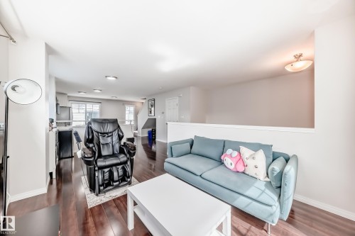 Open-concept living space with dark wood-finish flooring, recessed lighting, and a partial wall defining the living area - 45 4850 Terwillegar Common, Edmonton, AB - Indoor Photo Showing Living Room