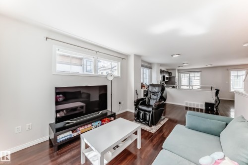 Open-concept living area with dark wood-finish flooring, white baseboards, and neutral wall paint - 45 4850 Terwillegar Common, Edmonton, AB - Indoor Photo Showing Living Room