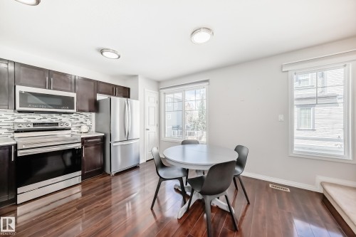 Kitchen featuring wood-finish flooring, dark wood cabinetry, and stainless steel appliances - 45 4850 Terwillegar Common, Edmonton, AB - Indoor