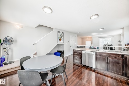 Open-concept living space featuring wood-finish flooring, recessed lighting, and a kitchen with dark cabinetry and stainless steel appliances - 45 4850 Terwillegar Common, Edmonton, AB - Indoor