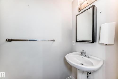 Pedestal sink with chrome faucet, framed mirror, and wall-mounted light fixture - 45 4850 Terwillegar Common, Edmonton, AB - Indoor Photo Showing Bathroom