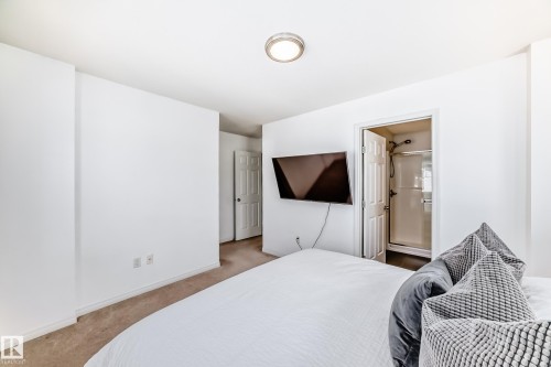 Carpeted room with white walls, a flush-mount ceiling light, and a six-panel interior door - 45 4850 Terwillegar Common, Edmonton, AB - Indoor Photo Showing Bedroom