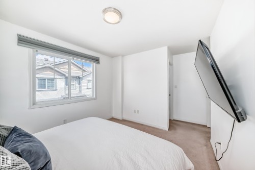 Carpeted room with white walls, a large window with a gray roller shade, and a flush mount ceiling light - 45 4850 Terwillegar Common, Edmonton, AB - Indoor Photo Showing Bedroom