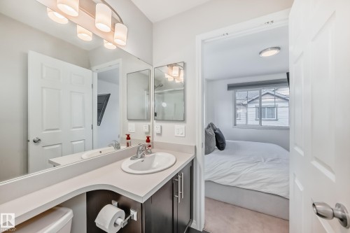 Bathroom vanity featuring an integrated sink, polished chrome faucet, and expansive mirror - 45 4850 Terwillegar Common, Edmonton, AB - Indoor Photo Showing Bathroom