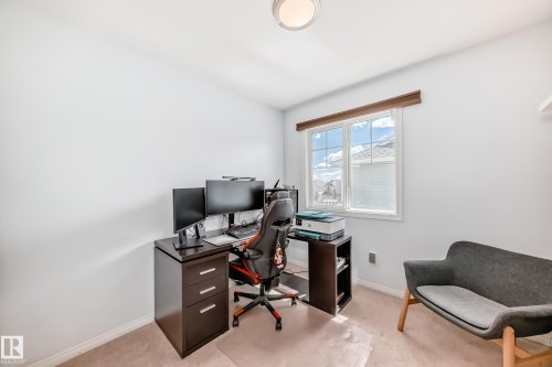 Bright room featuring a window with white blinds, neutral carpeting, and a flush-mount ceiling light fixture - 45 4850 Terwillegar Common, Edmonton, AB - Indoor Photo Showing Office