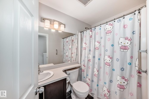 Bathroom featuring a dark wood-finish vanity with an integrated sink, a neutral-toned countertop, and a wall-mounted light fixture - 45 4850 Terwillegar Common, Edmonton, AB - Indoor Photo Showing Bathroom