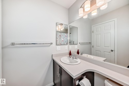 Bathroom featuring a dark wood-finish vanity with a light countertop, an integrated sink, and a chrome faucet - 45 4850 Terwillegar Common, Edmonton, AB - Indoor Photo Showing Bathroom