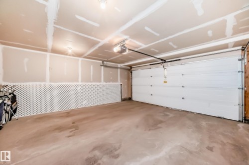 Spacious garage featuring a concrete floor, an overhead garage door opener, and unfinished drywall walls - 45 4850 Terwillegar Common, Edmonton, AB - Indoor Photo Showing Garage