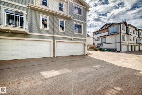 Exterior featuring two garages with white panel doors, light grey siding, and white trim windows - 45 4850 Terwillegar Common, Edmonton, AB - Outdoor