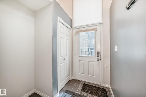 Entryway featuring a paneled door with glass insert, transom window, bi-fold closet doors, and tile flooring - 45 4850 Terwillegar Common, Edmonton, AB - Indoor Photo Showing Other Room