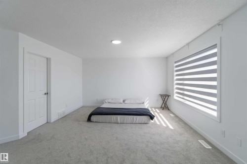 Bedroom featuring light gray carpeting, a window with horizontal blinds, and a white six-panel door - 1017 82 Street, Edmonton, AB - Indoor Photo Showing Other Room