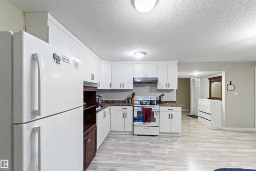 The kitchen features white cabinetry and a white refrigerator, complemented by a light-colored floor - 1017 82 Street, Edmonton, AB - Indoor Photo Showing Kitchen With Double Sink