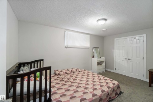 This room features light gray walls, a textured ceiling, and a window with blinds - 1017 82 Street, Edmonton, AB - Indoor Photo Showing Bedroom
