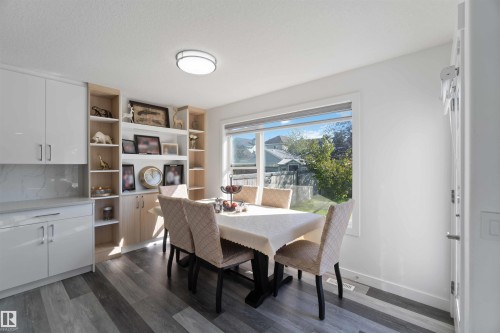 This bright dining area features a large window, built-in shelving, white cabinetry, and wood-style flooring - 1017 82 Street, Edmonton, AB - Indoor Photo Showing Dining Room