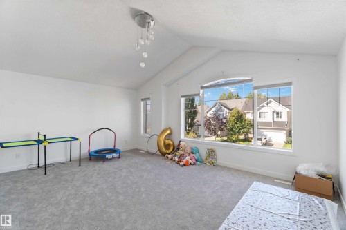 Spacious room featuring vaulted ceilings, a contemporary chandelier, and large windows offering exterior views - 1017 82 Street, Edmonton, AB - Indoor