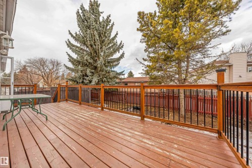 Spacious outdoor deck with wood-finish flooring and wood railing featuring black balusters - 2437 89 Street, Edmonton, AB 