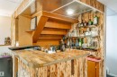 Custom bar area featuring a wood-finish countertop with metal trim, vertically paneled wood-finish walls, built-in shelving, and recessed lighting - 2437 89 Street, Edmonton, AB 