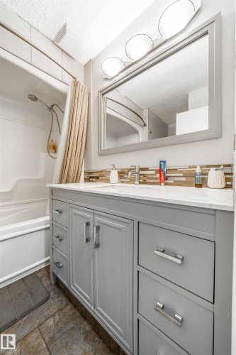 Bathroom featuring a light gray dual vanity with white countertop, chrome hardware, and a tile backsplash - 2437 89 Street, Edmonton, AB 
