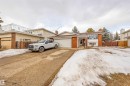 Brick and siding exterior featuring an attached two-car garage, bay window, and a concrete driveway - 2437 89 Street, Edmonton, AB 