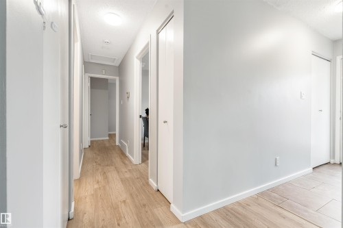 Hallway featuring light wood-finish flooring, white baseboards, and neutral wall paint - 2437 89 Street, Edmonton, AB 