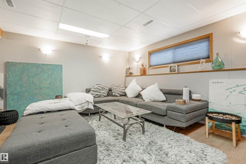 Finished room with recessed paneling, wood-framed horizontal window with shades, wall sconces, and a suspended ceiling with integrated lighting - 2437 89 Street, Edmonton, AB 