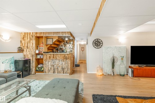 Finished basement with a built-in bar featuring wood-panel accents and shelving - 2437 89 Street, Edmonton, AB 