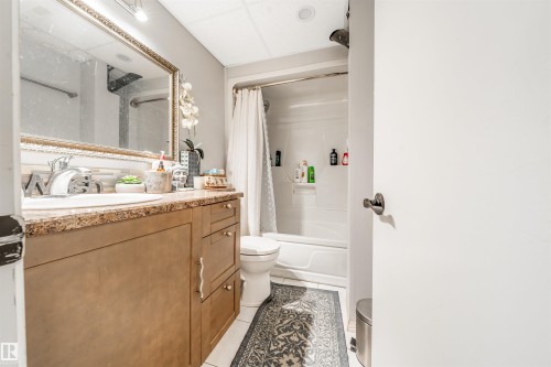 Bathroom featuring a single vanity with a stone countertop, an integrated sink, and a framed mirror - 2437 89 Street, Edmonton, AB 
