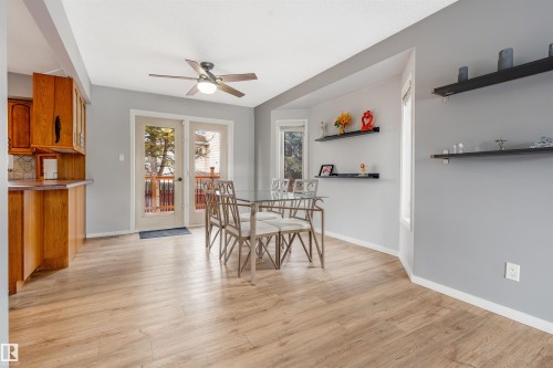Dining area featuring wood-finish flooring, a ceiling fan with integrated lighting, and dual glass-paneled doors opening to an exterior deck - 2437 89 Street, Edmonton, AB 